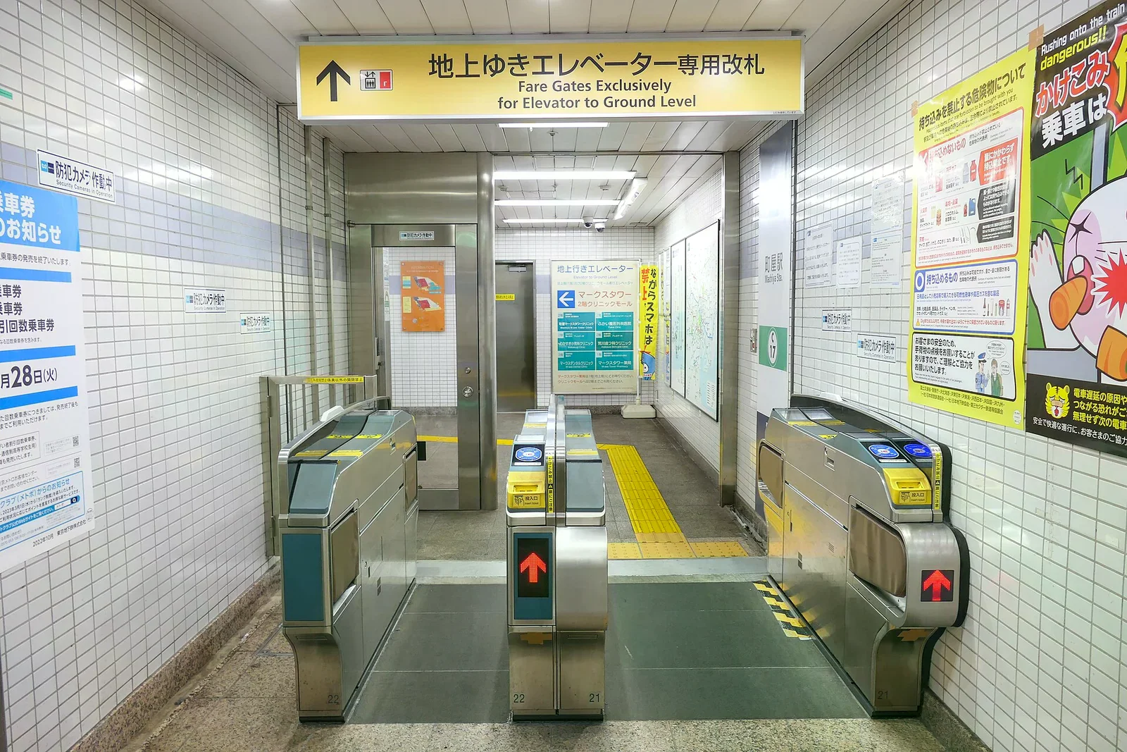 東京地鐵車站內通往地面電梯的專用改札口，上方黃色看板寫著電梯專用，地面有黃色警示磚，兩側是 IC 感應閘門