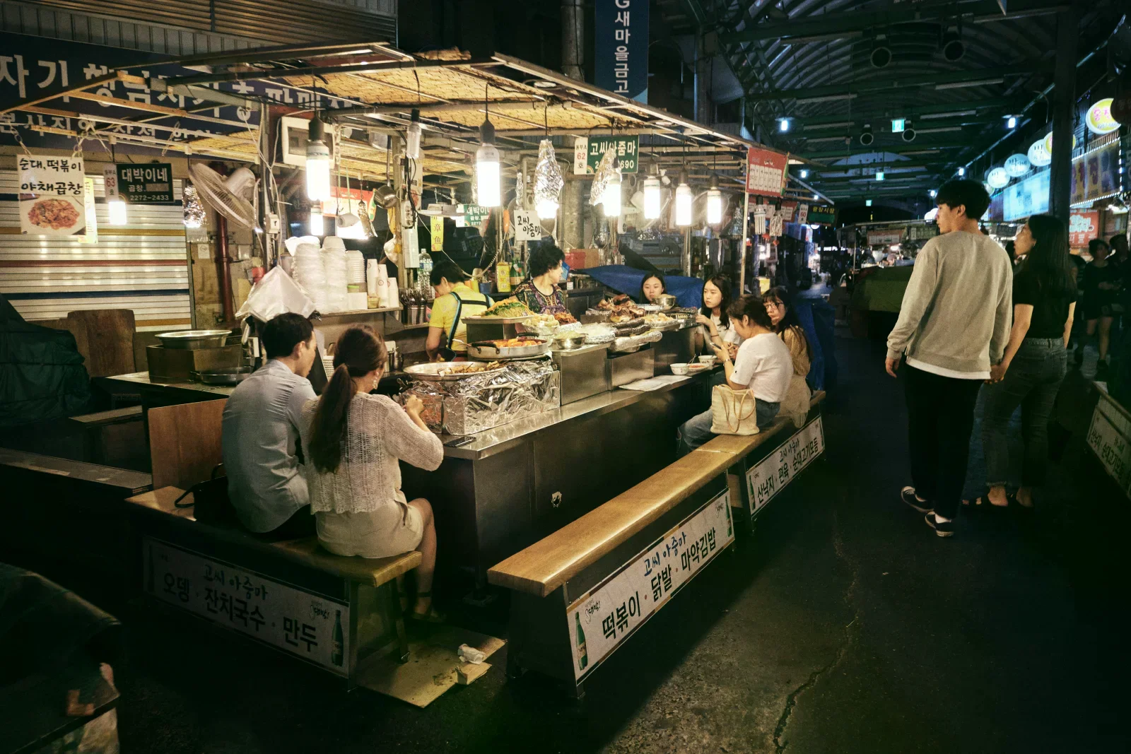 夜市走道擠滿顧客，兩側可見攤位與燈光