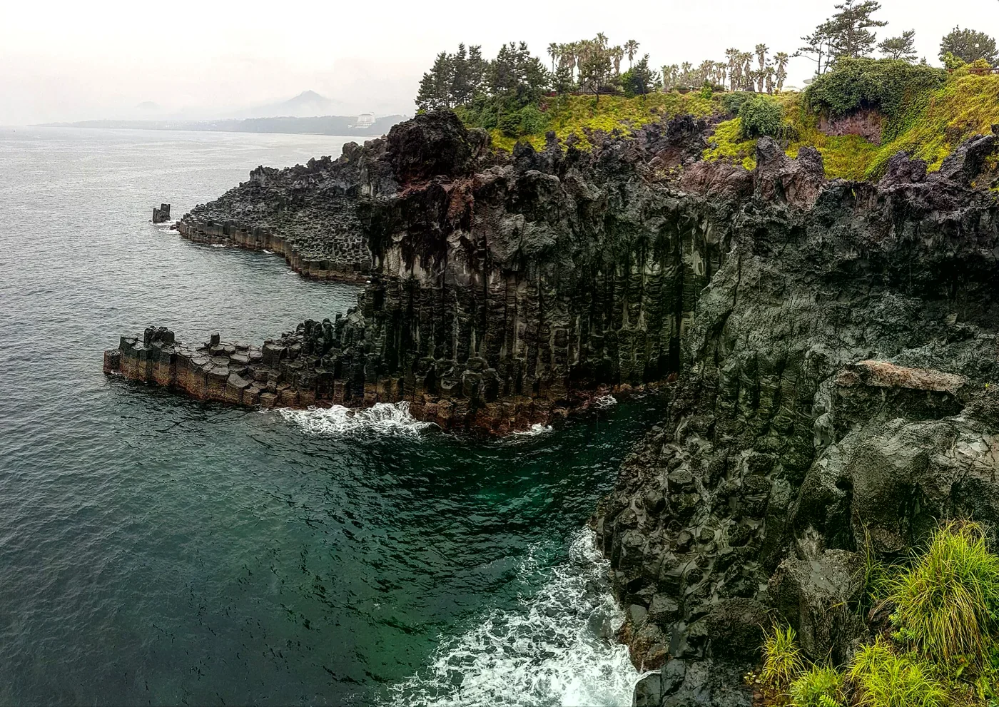 濟州島黑色柱狀岩壁、海面與岸上的綠色植被