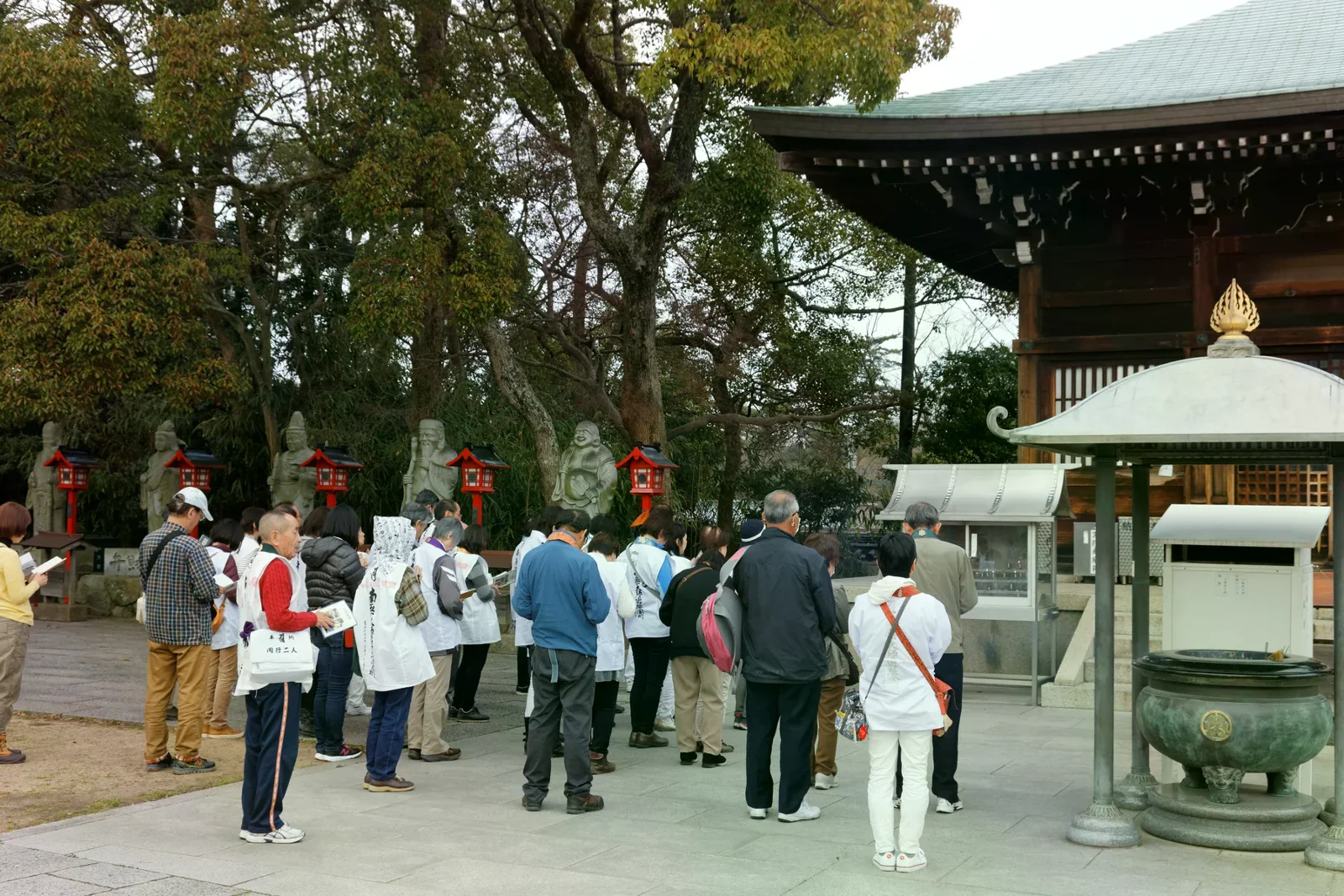 屋島寺境內的香爐前，數名穿白色遍路衣的參拜者合掌