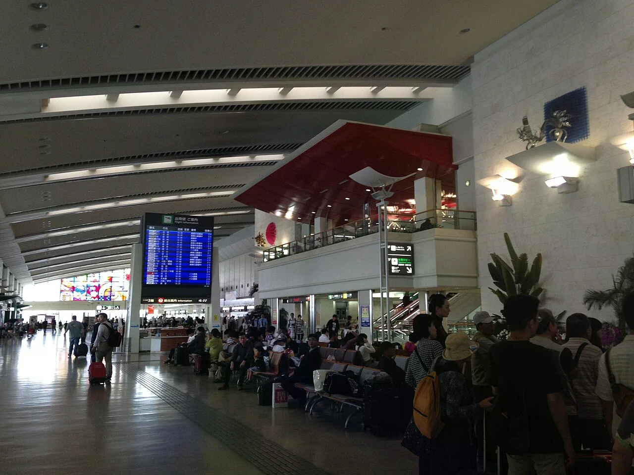 那霸機場國內線旅客航廈二樓候機區，旅客座椅與航班資訊牌清楚可見