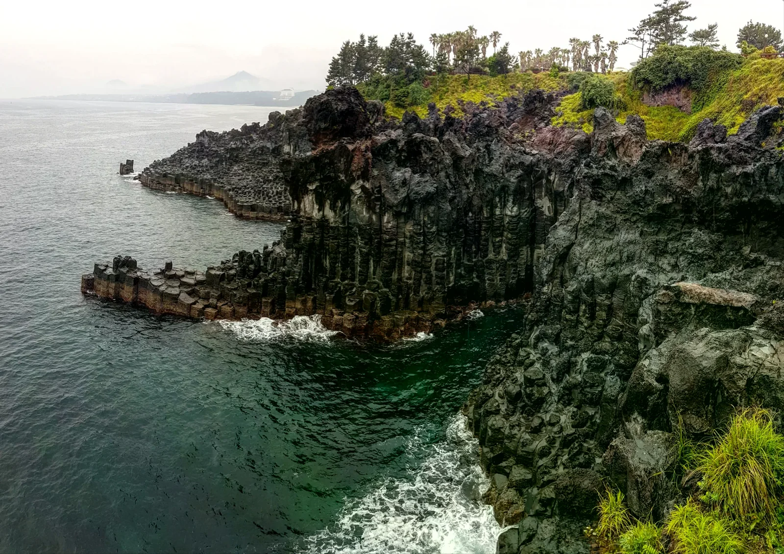 濟州島大浦柱狀節理海岸岩壁和海面，作為外出行程的目的地情境照片