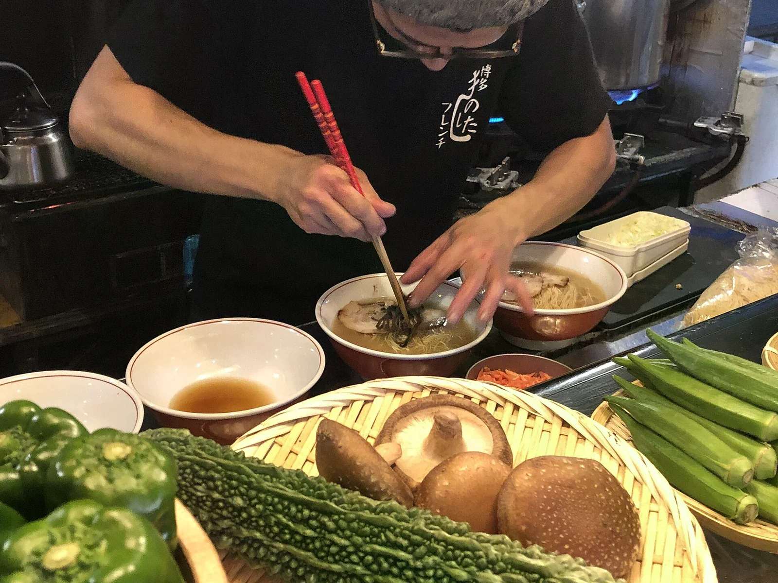 雙手用筷子整理福岡屋台拉麵碗中的配料