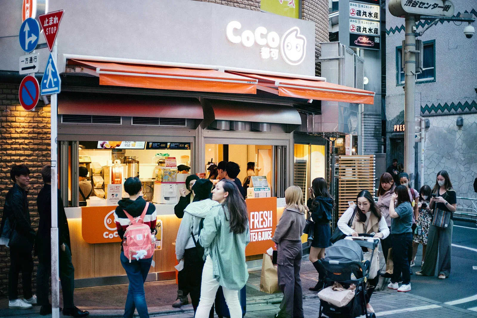 東京澀谷 Center-gai 街角，一間飲料攤前站滿排隊的年輕人與觀光客，街牌上寫著澀谷センター街