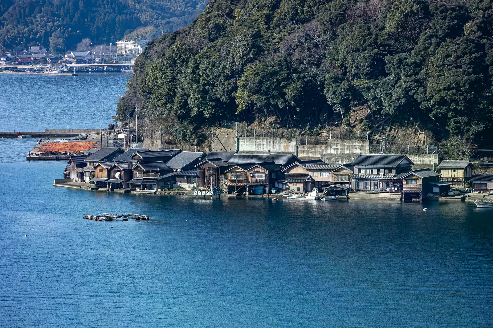 靠岸處幾棟舟屋沿灣並列，前方海面有小型浮台與停泊設施