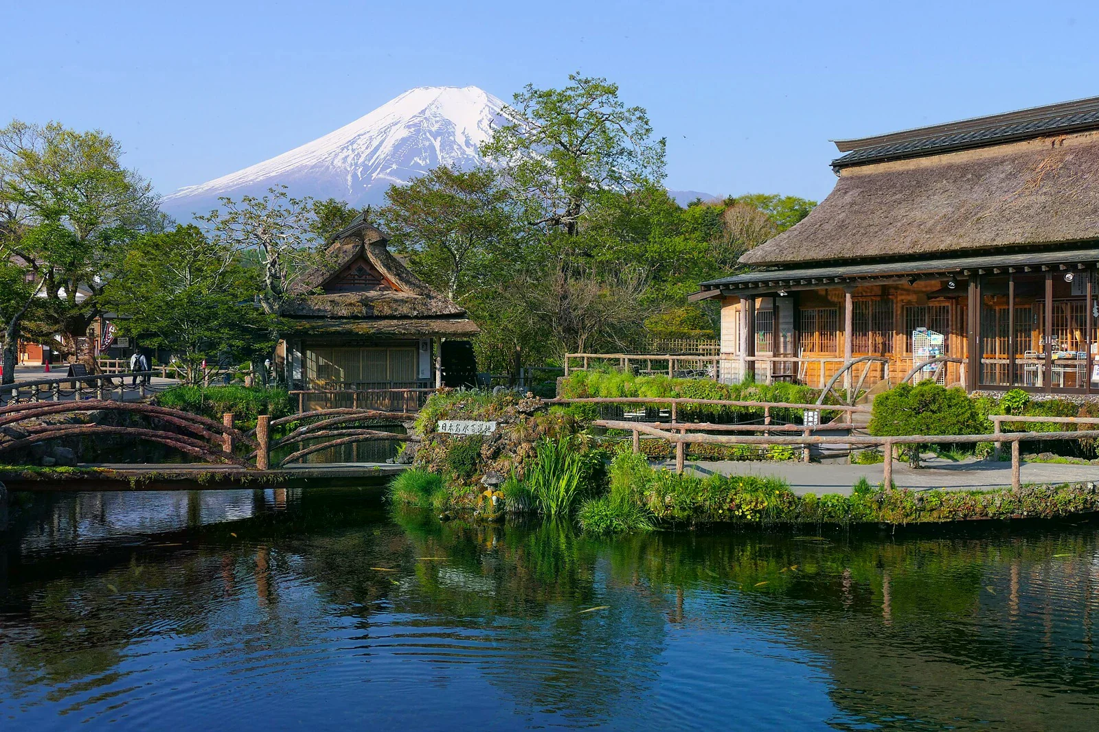 忍野八海中池、池畔茅草屋與富士山。