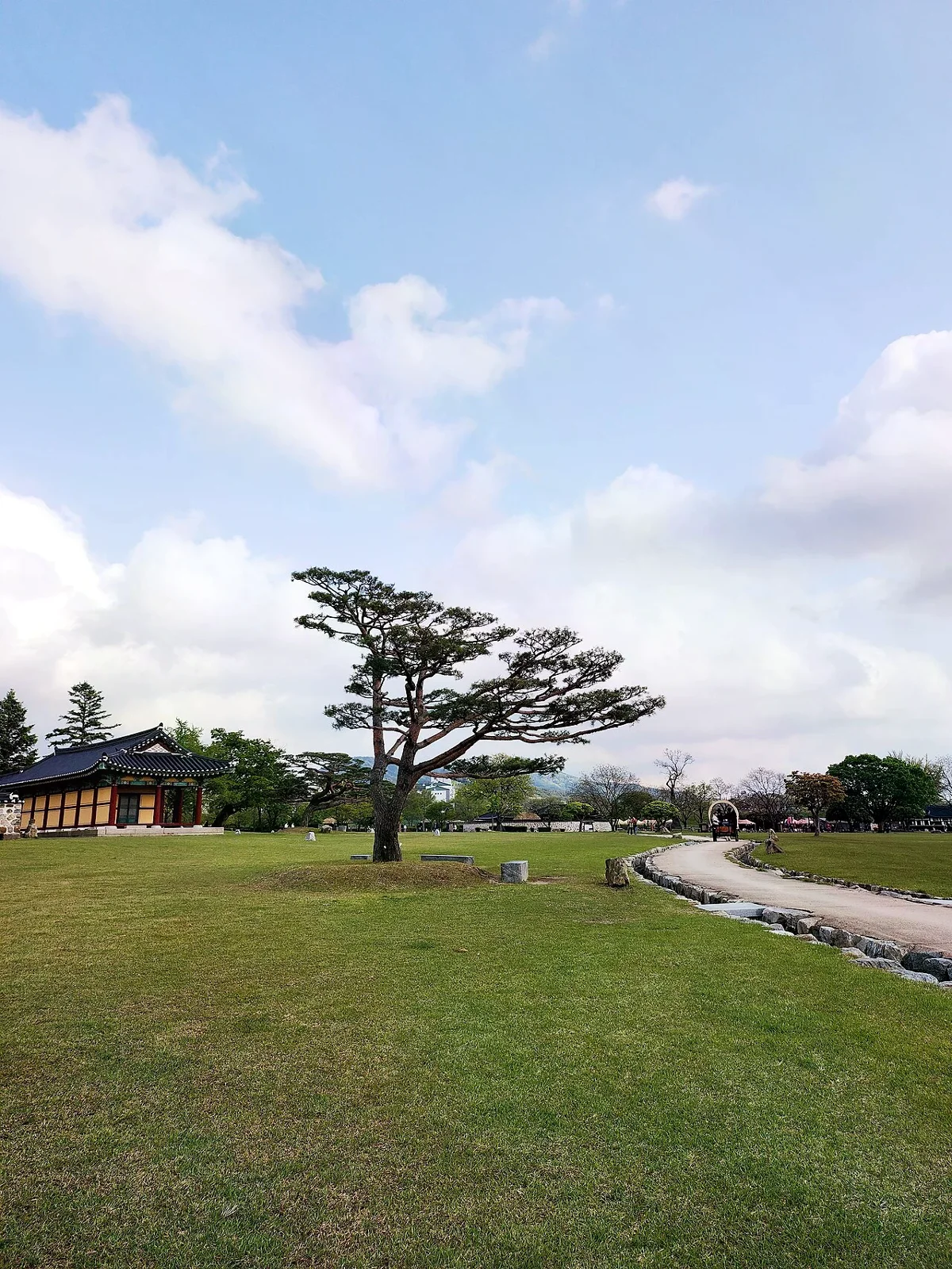 海美邑城內的松樹、草地與傳統建築，步道沿草地向城內延伸