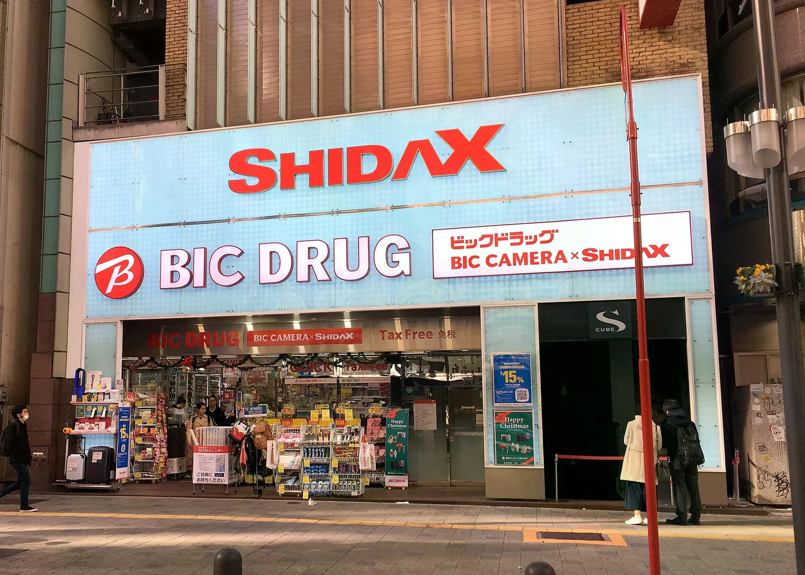 東京新宿一間 BIC DRUG 藥妝店門面，淺藍色大型招牌上有紅色 BIC DRUG 字樣，入口上方明顯掛著 Tax Free 免稅標示