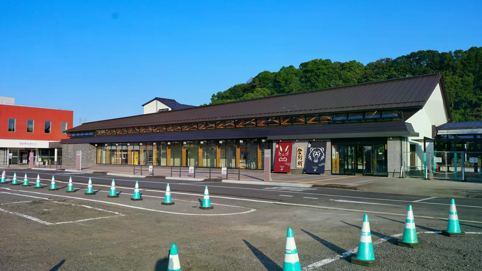 登別站新站舍的長棕色斜屋頂與入口前綠白交通錐