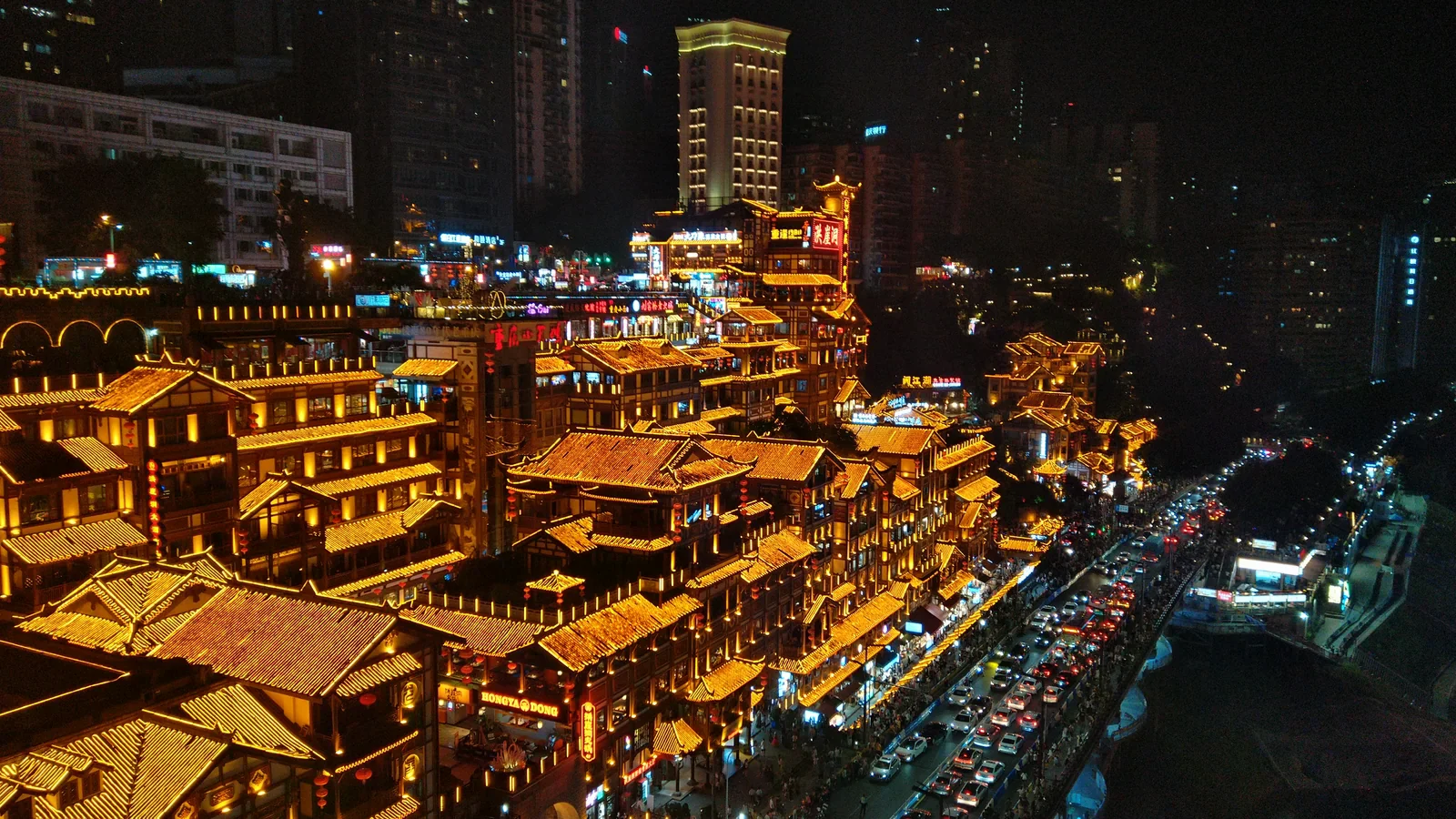 重慶洪崖洞夜景，木質吊腳樓群層層疊疊亮起金黃色燈光，旁邊馬路車流燈河。