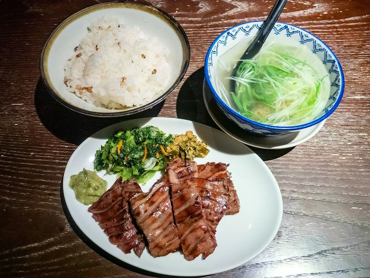 白盤上的烤牛舌定食，旁邊有飯、清湯和漬物