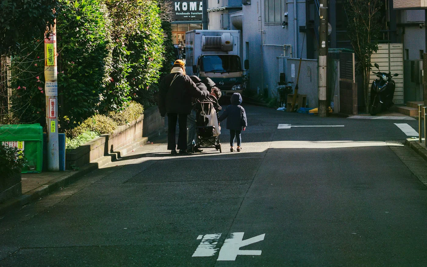 家長推著推車與孩子走在窄巷中，呈現親子城市旅行情境