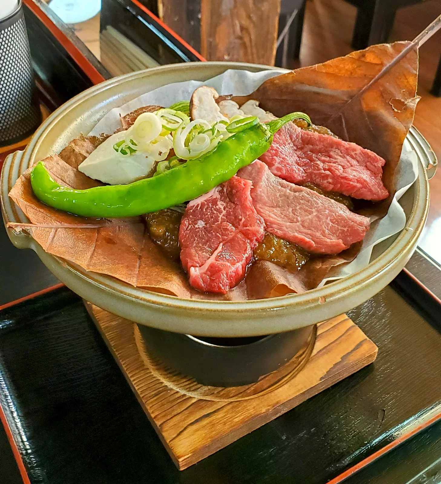 朴葉上放著飛驒牛肉片、蔥與蔬菜，置於小鍋中加熱