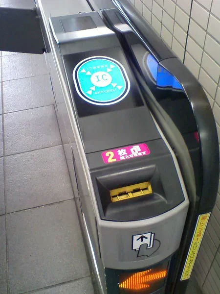 PASMO 改札機面板近照，圓形 IC 感應區與票卡插入口、箭頭指示燈