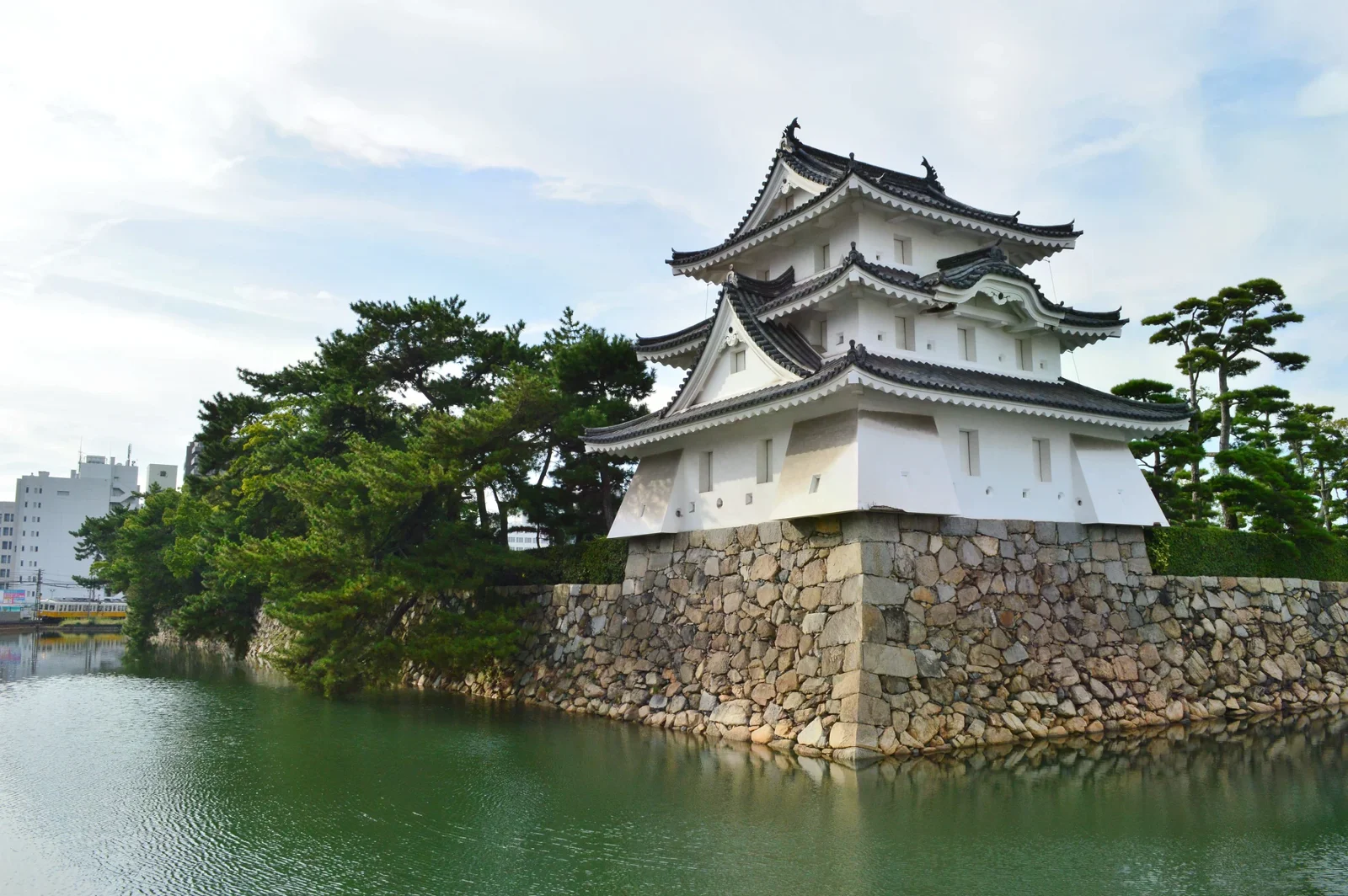 玉藻公園水濠旁的白色艮櫓、石垣與松樹（2017 年照片）。