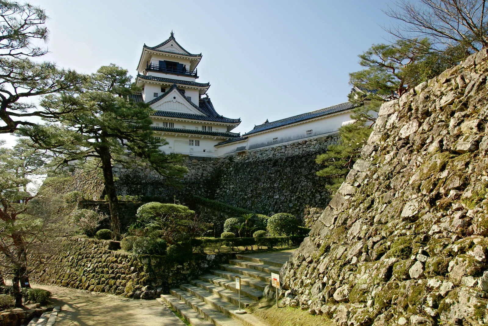 白石多層天守踞於灰白石垣上，旁有松樹與石階