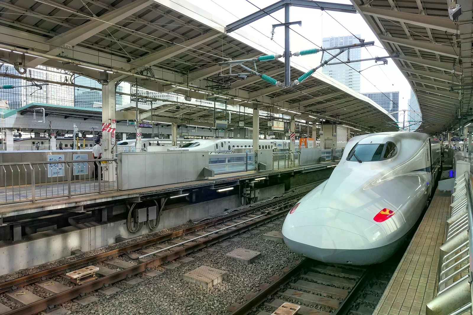 東京車站月台上停靠的 N700 系新幹線車頭，對面月台可見另一列車與車站雨棚。