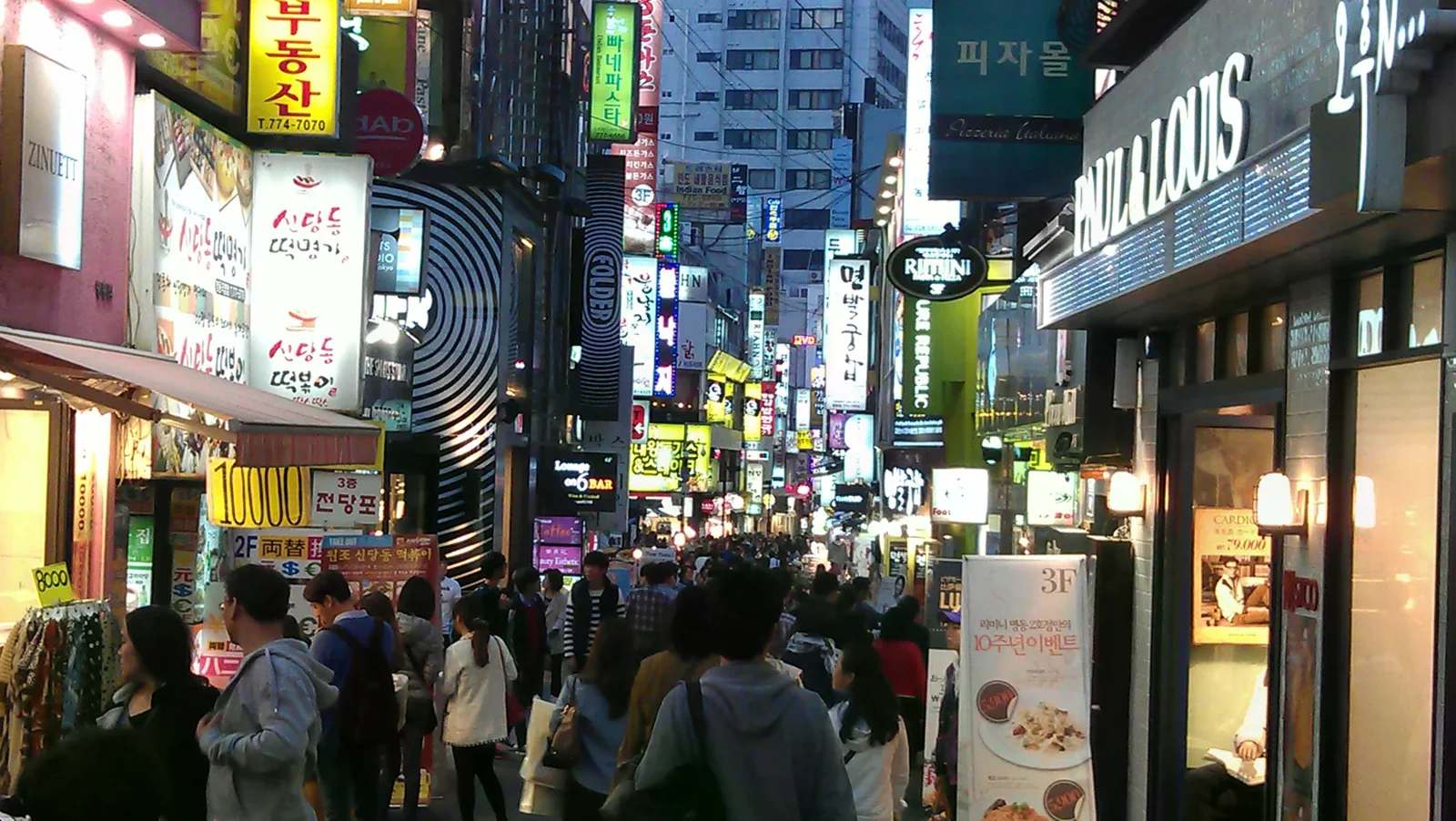 2012 年夜間明洞街道、店面招牌與行人，呈現首爾觀光區街景