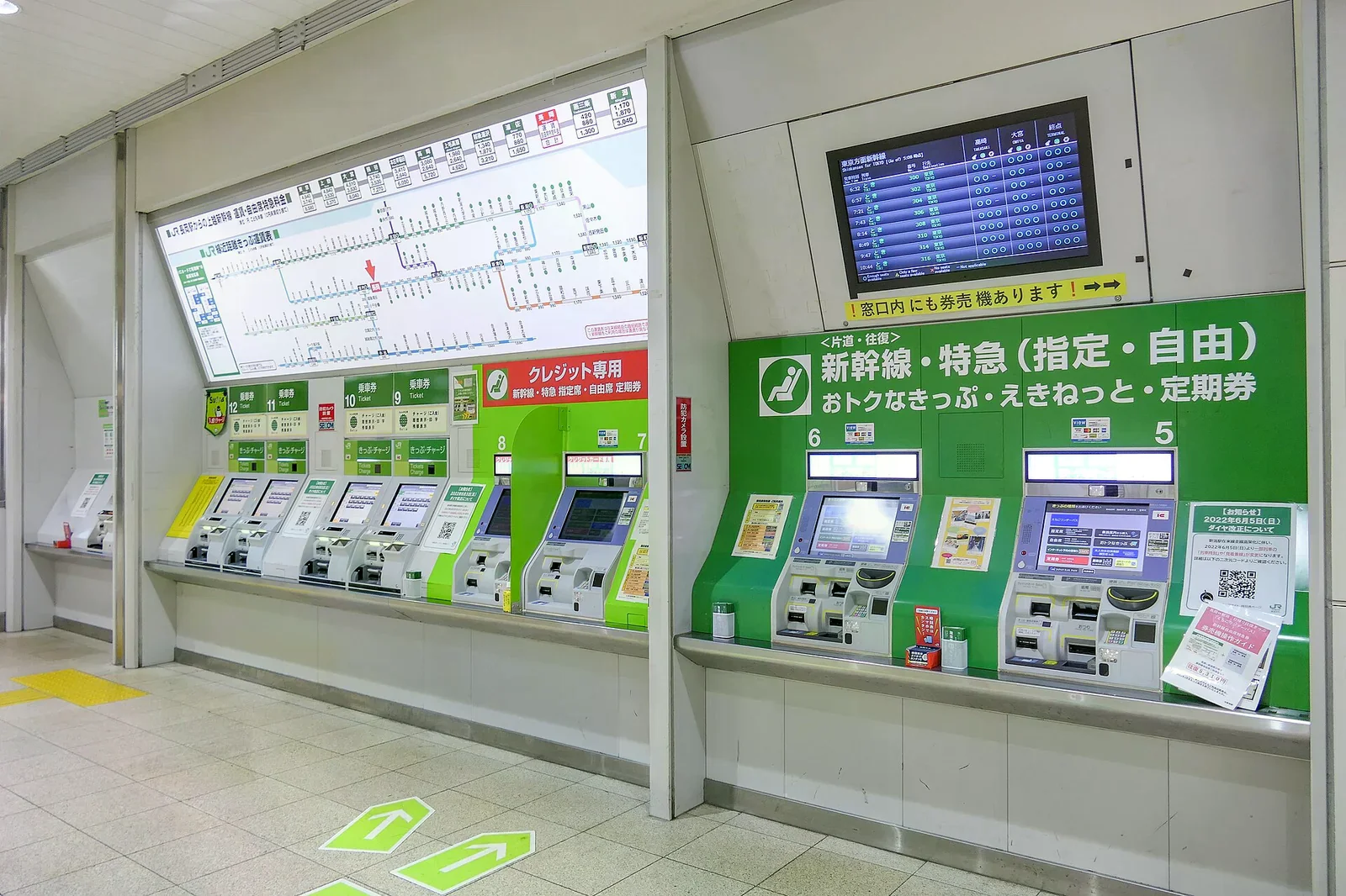 JR 車站內多台自助售票機，上方有運費表與時刻表，地面有綠色方向標示