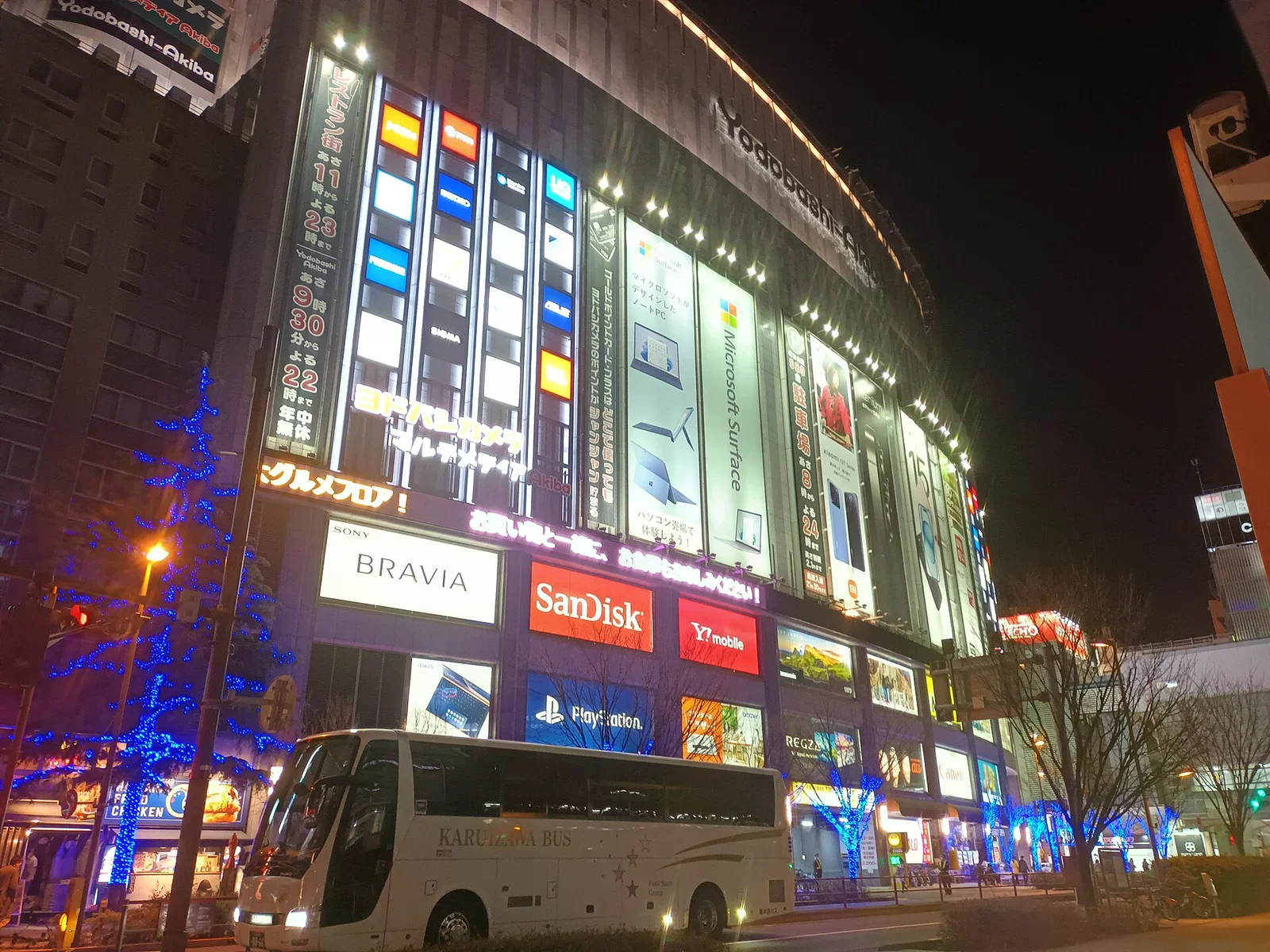 夜晚的友都八喜秋葉原店大樓外觀，外牆布滿 Sony、PlayStation、微軟等品牌廣告燈箱