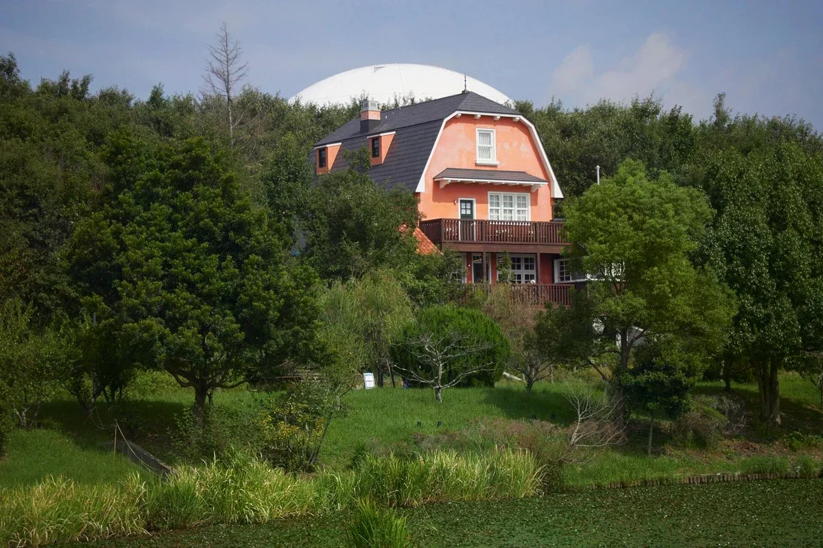 吉卜力公園內的粉橘色建築、樹林與白色穹頂。