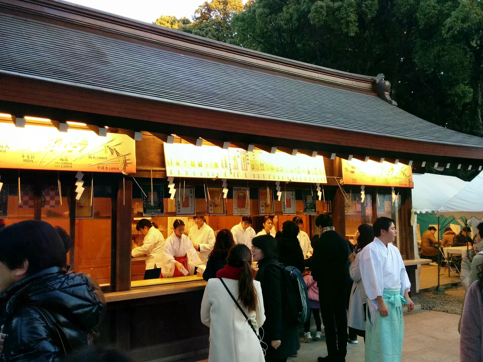 神社授與所櫃台擺放御守與護符，信眾在櫃前排隊