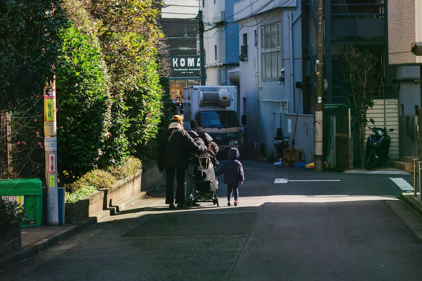 東京巷弄中，一位家長推著推車陪孩子行走