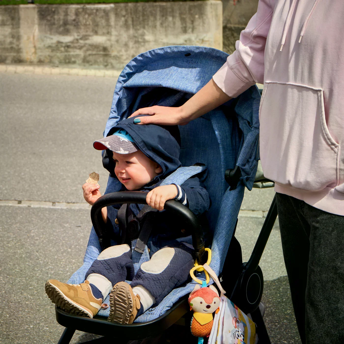 穿著藍色外套的孩子坐在推車裡，大人在旁陪伴