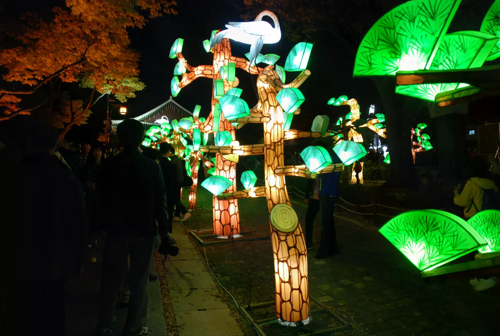 2011 年晉州南江流燈節夜間展出的大型發光燈組，前景有散步觀眾