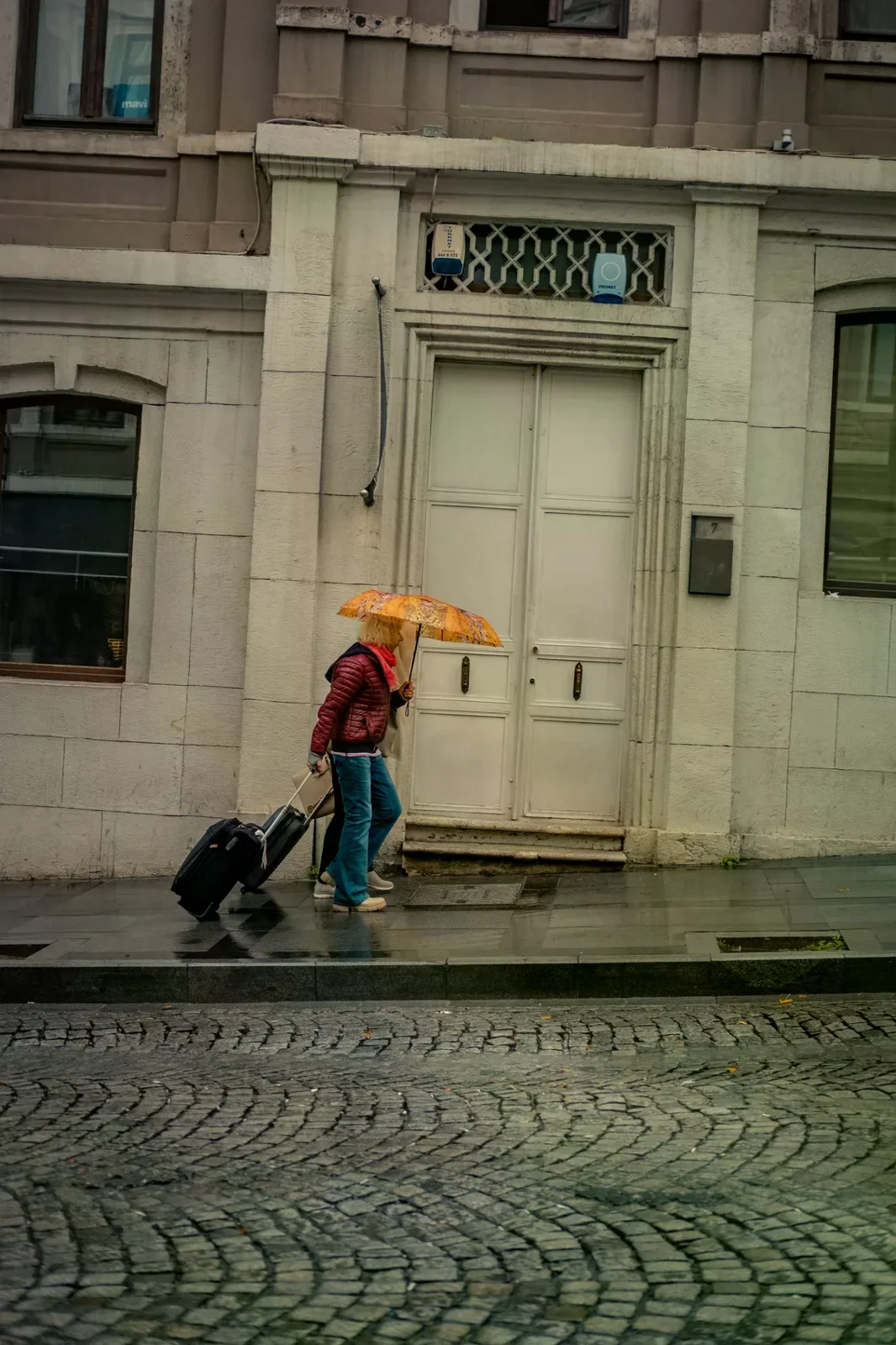 一名旅人在雨天撐傘並拉著行李箱，情境示意，非金澤實景