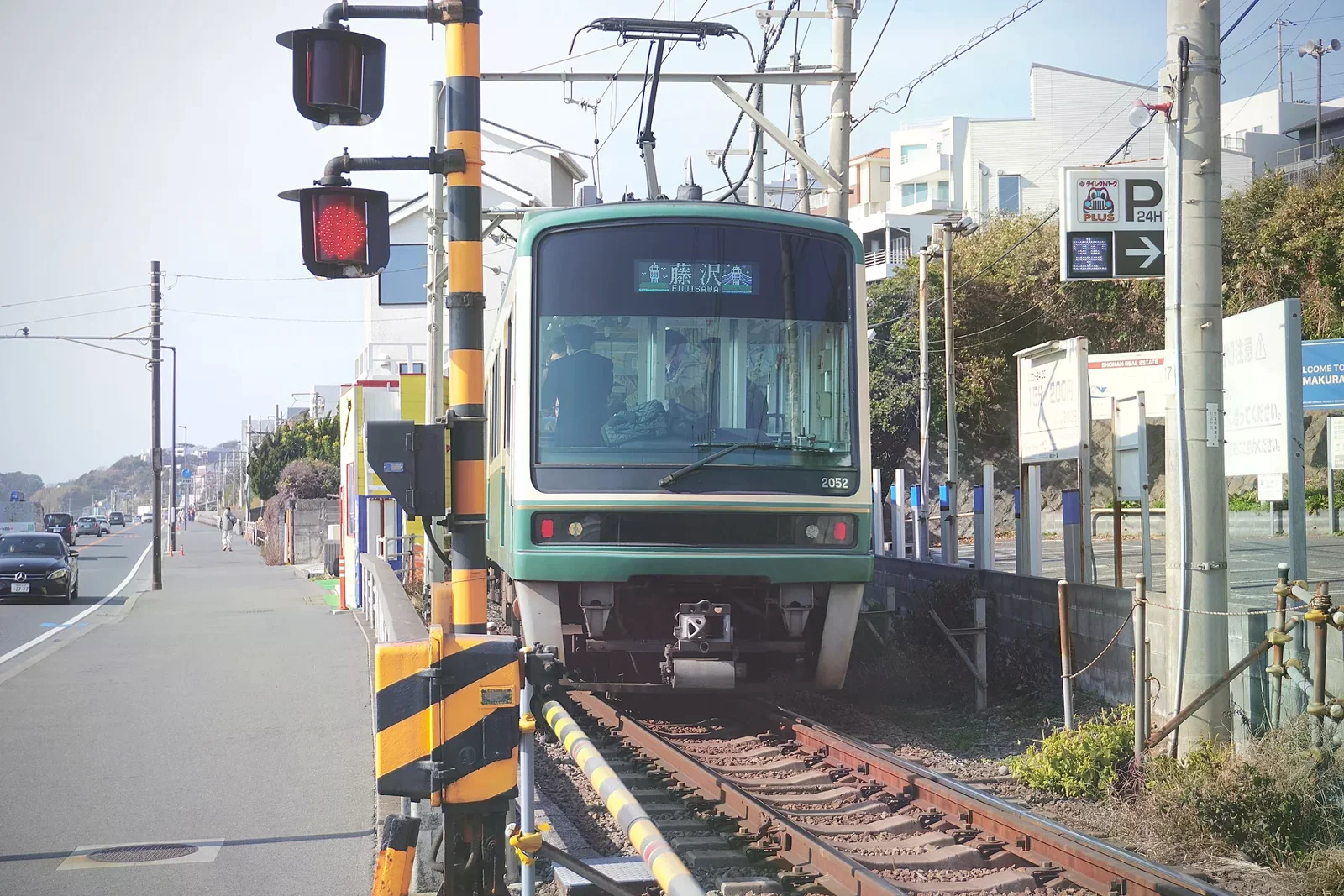 綠色江之電列車行經鎌倉街區的情境照
