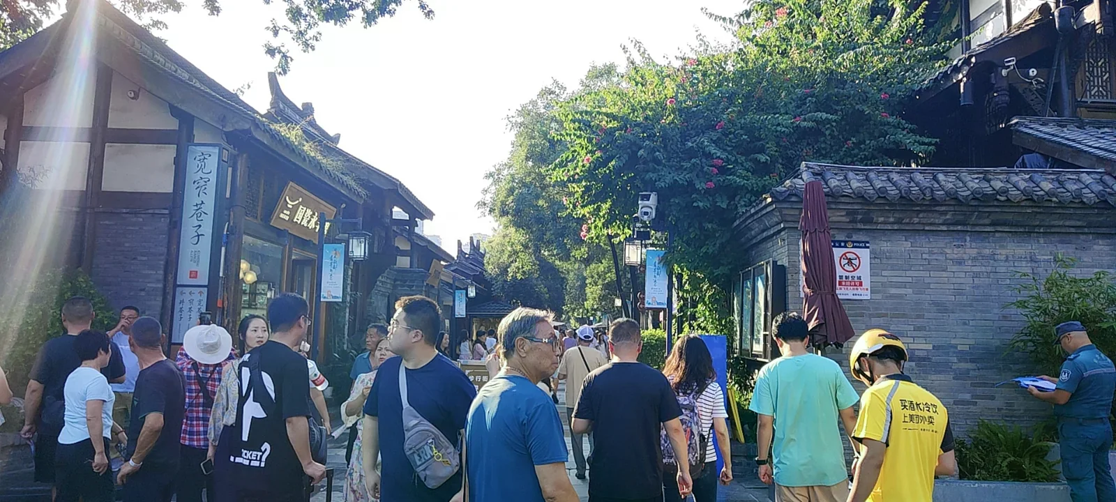寬窄巷子入口，傳統川西木構建築與遊客步行街道，左側豎幅寫有「寬窄巷子」四字。