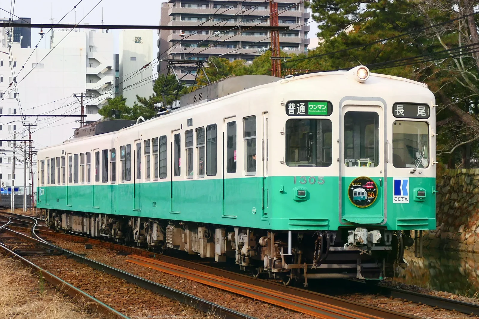 琴電綠白色1300形列車停靠都市路線，車頭掛著五十周年紀念牌（2025 年照片）。
