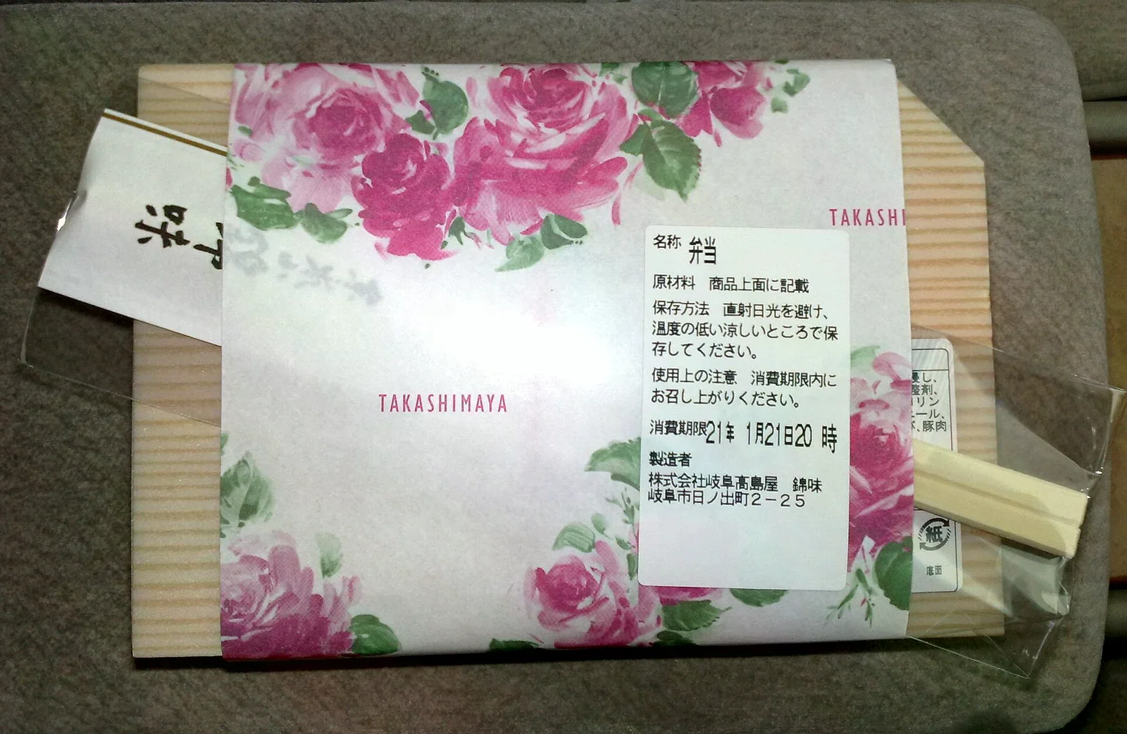 以花卉包裝紙裹好的百貨食品，標籤上寫著消費期限與直射日光避開、陰涼處保存的保存方法