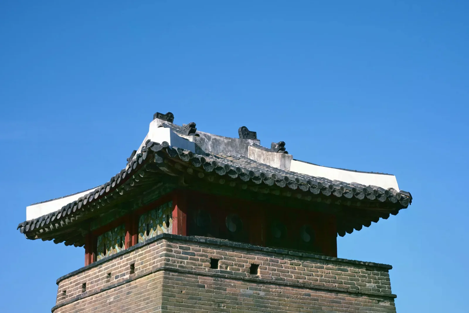 水原華城城牆上一座石砌建築和傳統屋頂的仰角近景
