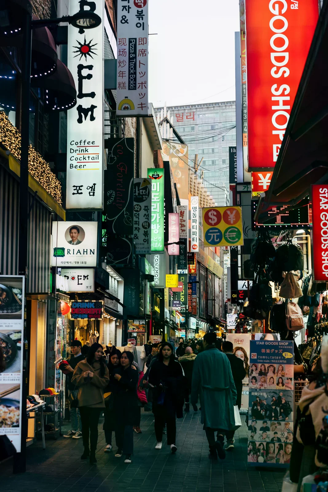 首爾商圈街道，兩側是招牌與店面，街上有行人