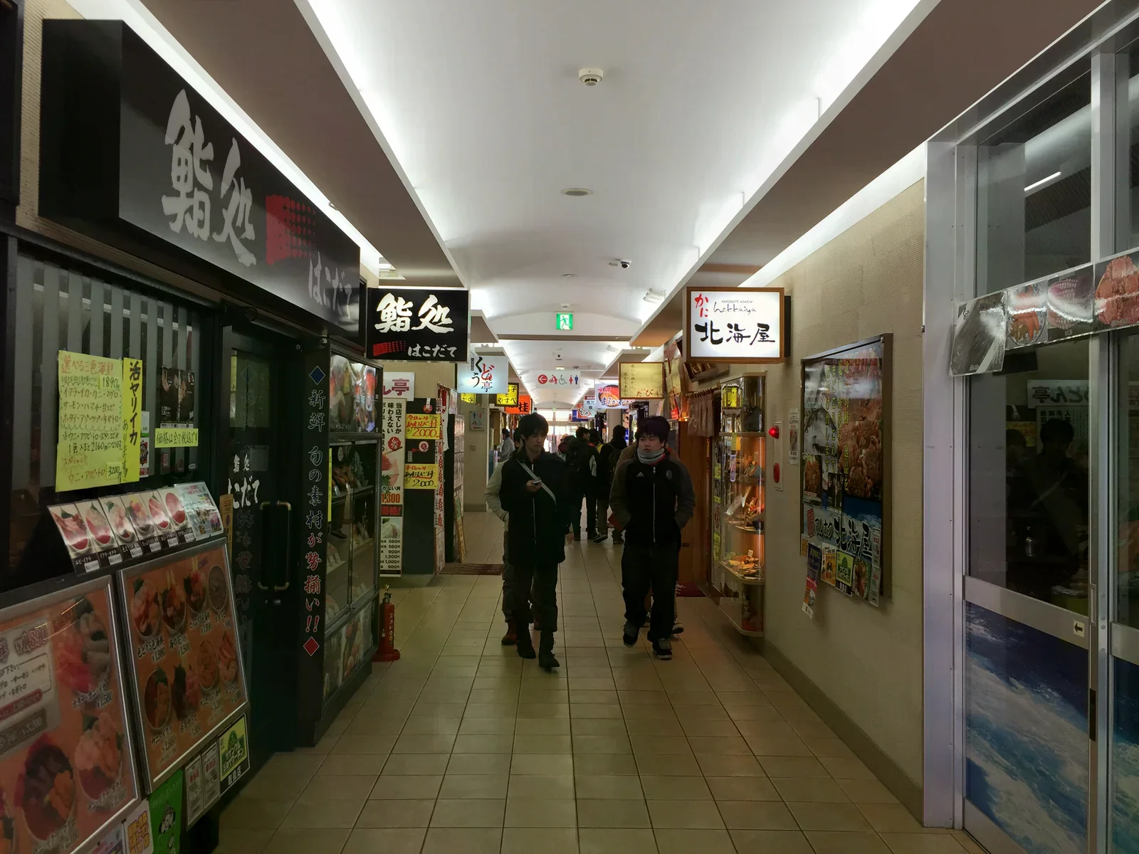 函館朝市室內通道兩側是海鮮餐飲店，門口展示料理照片