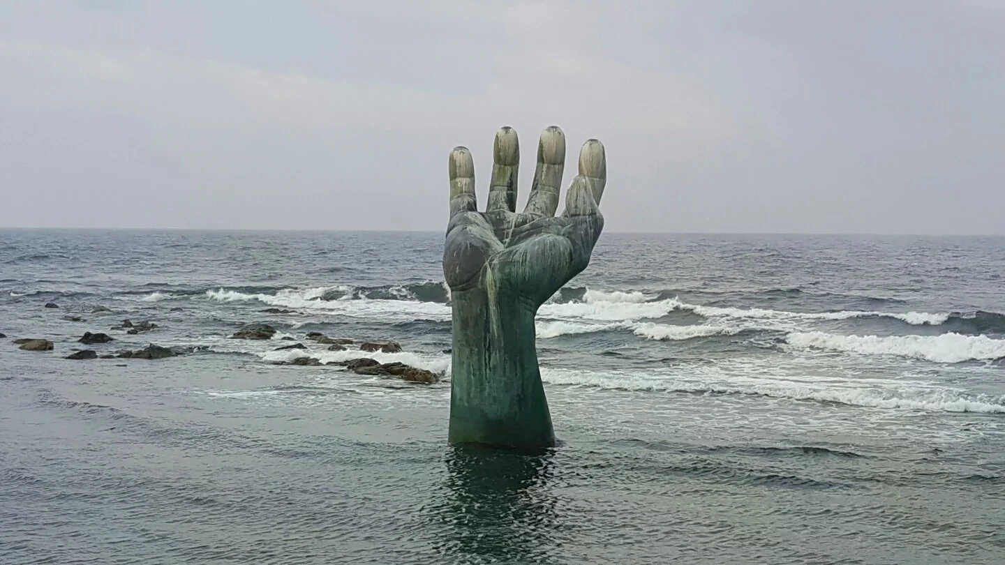 浦項虎尾岬海邊的兩座手形相生之手雕塑，近處在岸上，遠處立於海中