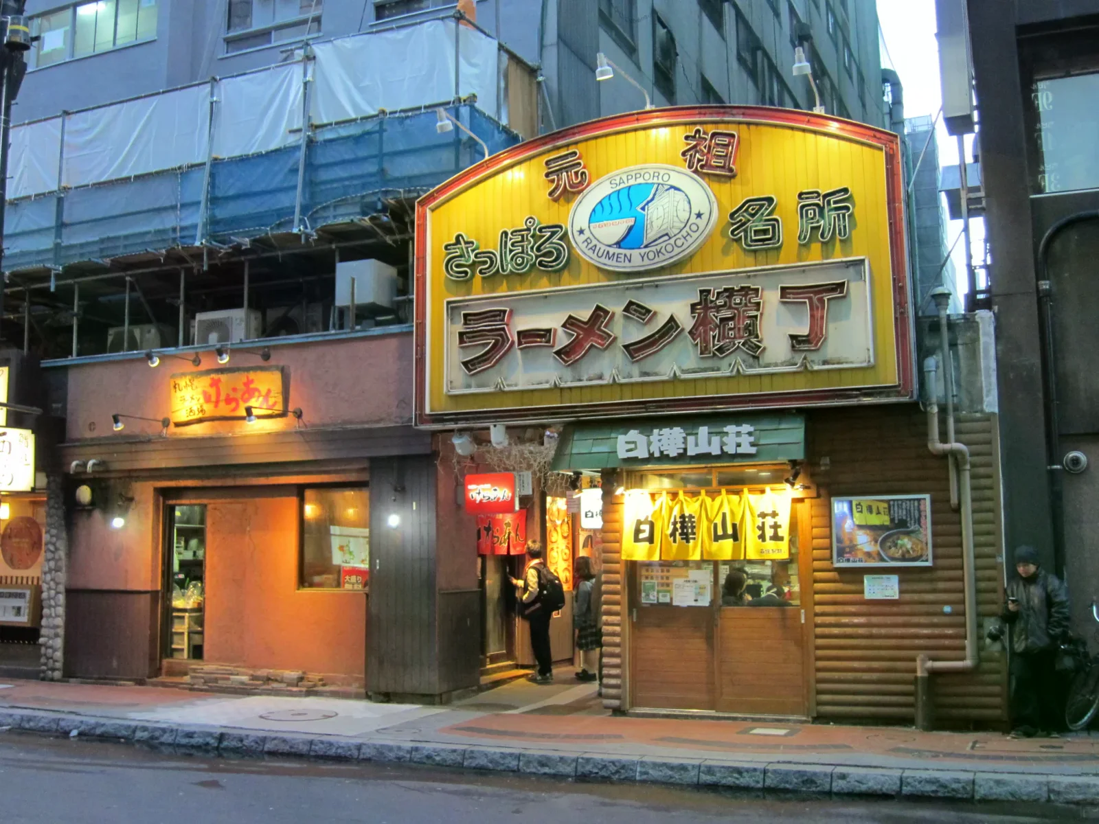 元祖札幌拉麵橫丁北側入口，黃色牌樓下方是窄巷與相鄰店門