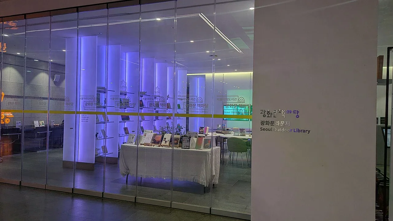 光化門 Lounge 玻璃門內的書籍展示與室內閱讀空間，牆面可見 Gwanghwamun Lounge 標牌
