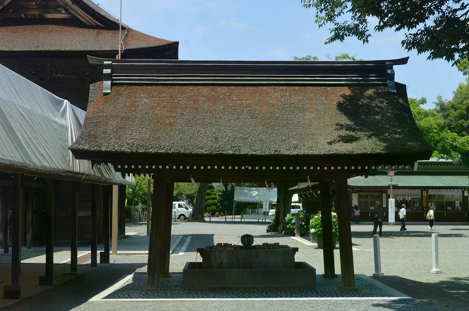 神社手水舍的茅草屋頂石製水池，長柄木勺整齊排在缽邊