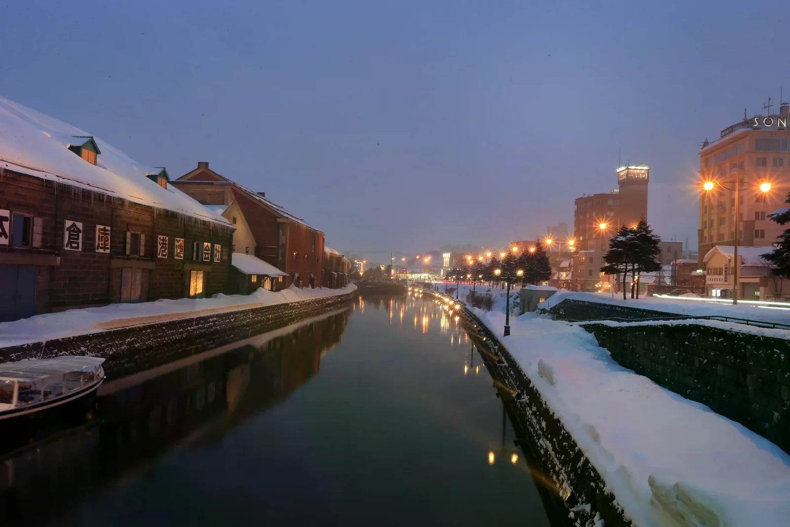 雪夜裡的小樽運河、倉庫與沿岸燈光，呈現冬季景色