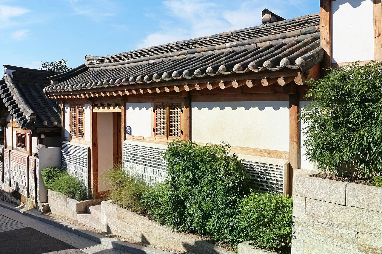 北村韓屋村一棟傳統住宅的瓦簷、木窗格、石牆與庭前植物