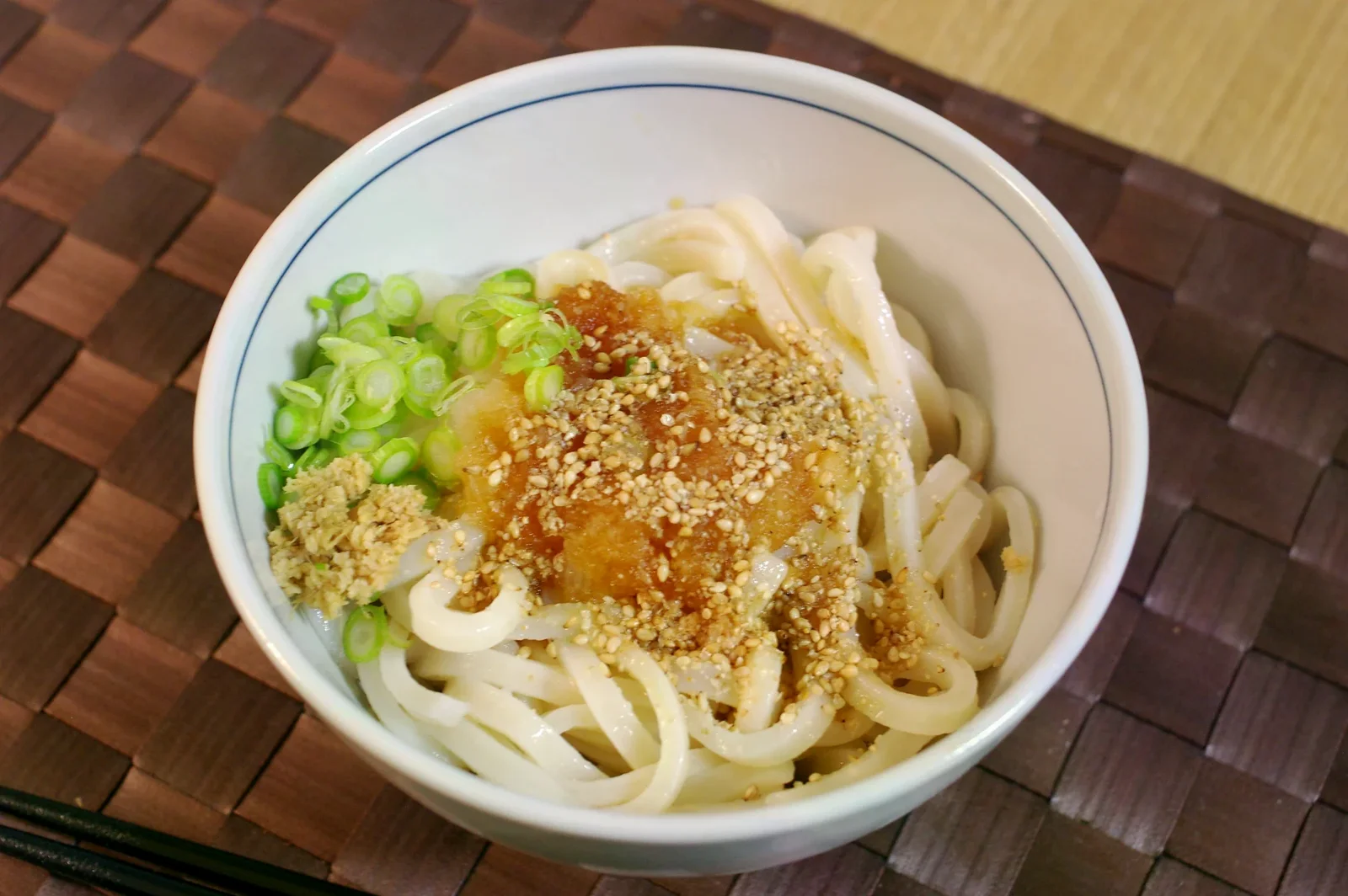 一碗冰烏龍麵放上蘿蔔泥、蔥、薑與芝麻。