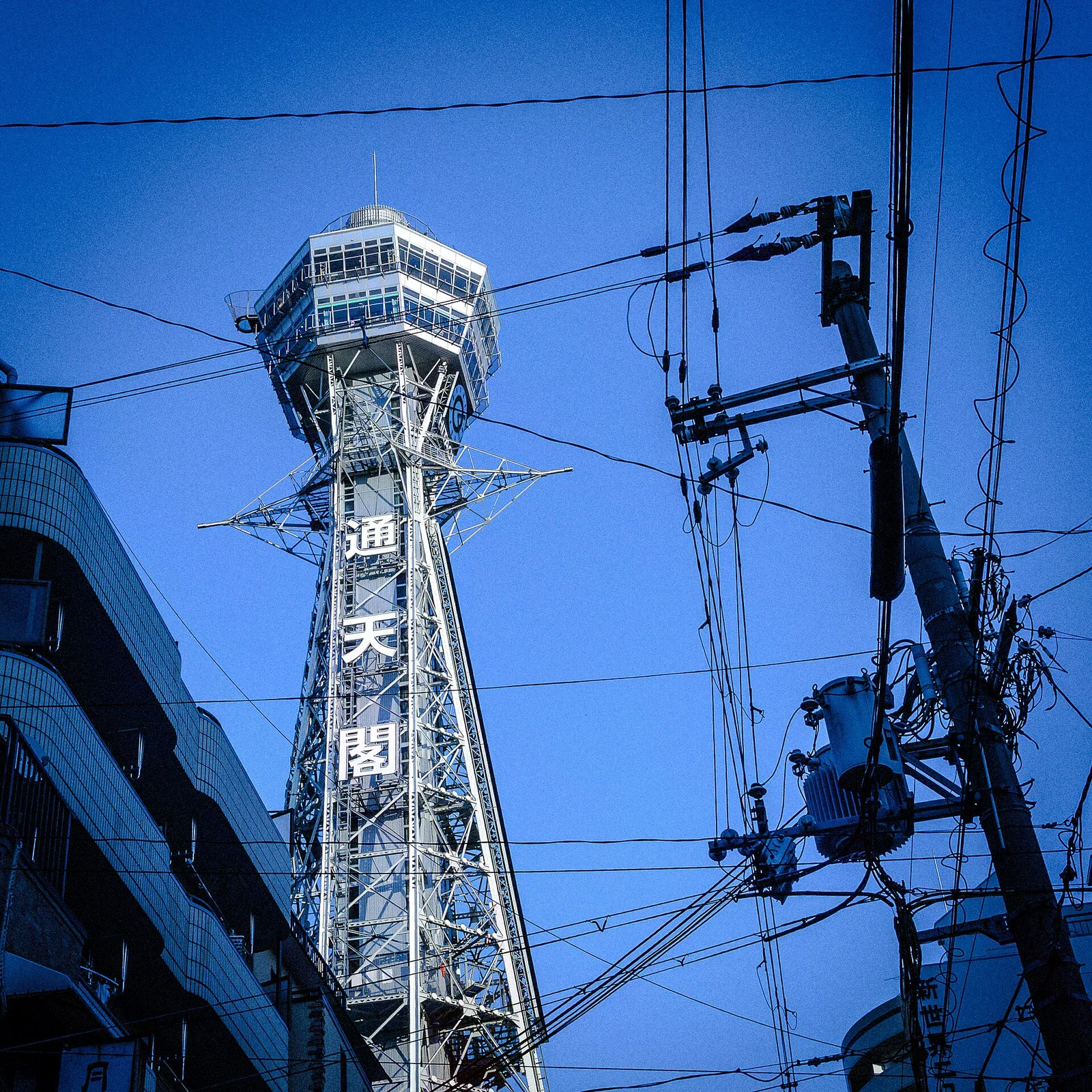 新世界街區上方的通天閣塔身與周邊電線。
