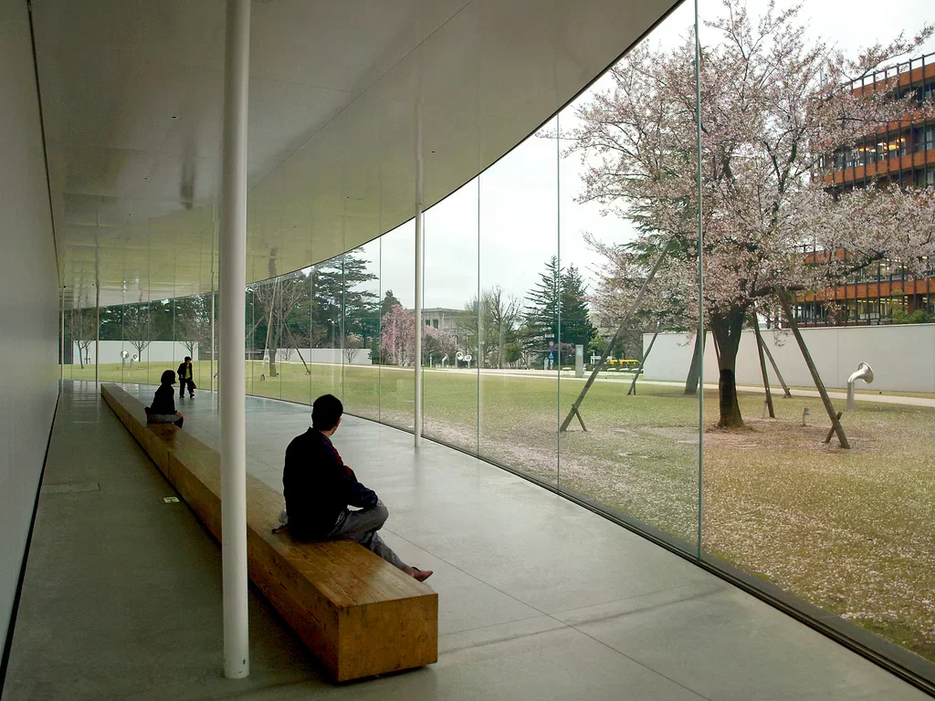 金澤21世紀美術館玻璃窗旁的長椅與盛開樹木，2010年照片