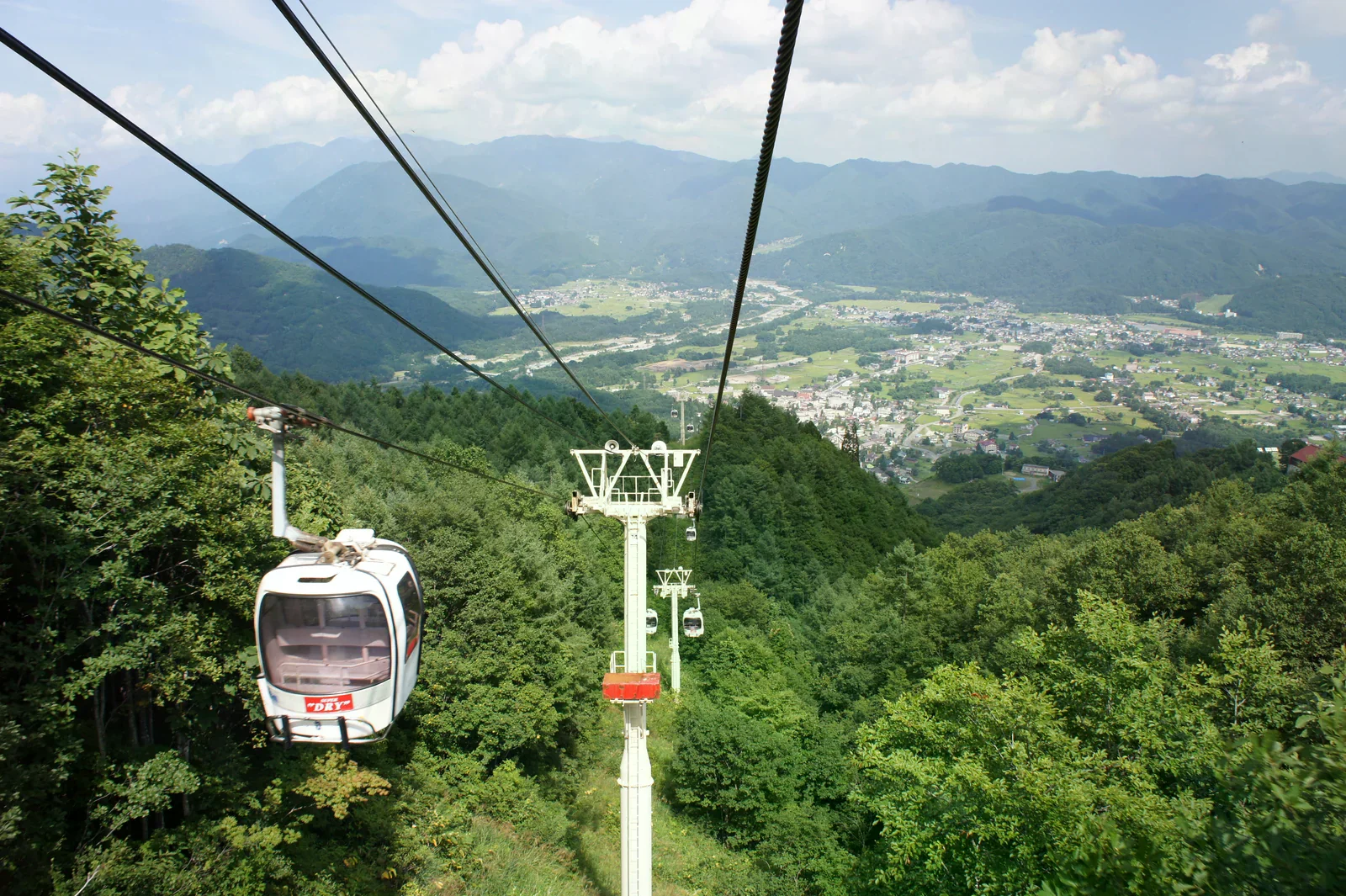 白馬八方尾根纜車沿山坡運行，遠處可見山谷聚落（2010 年畫面）。