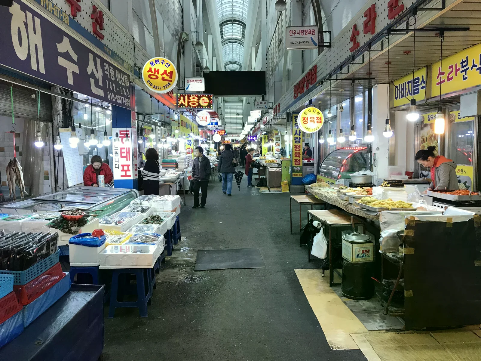 原州中央市場的室內走道與左右兩側傳統攤位，拱形半透明屋頂覆蓋通道