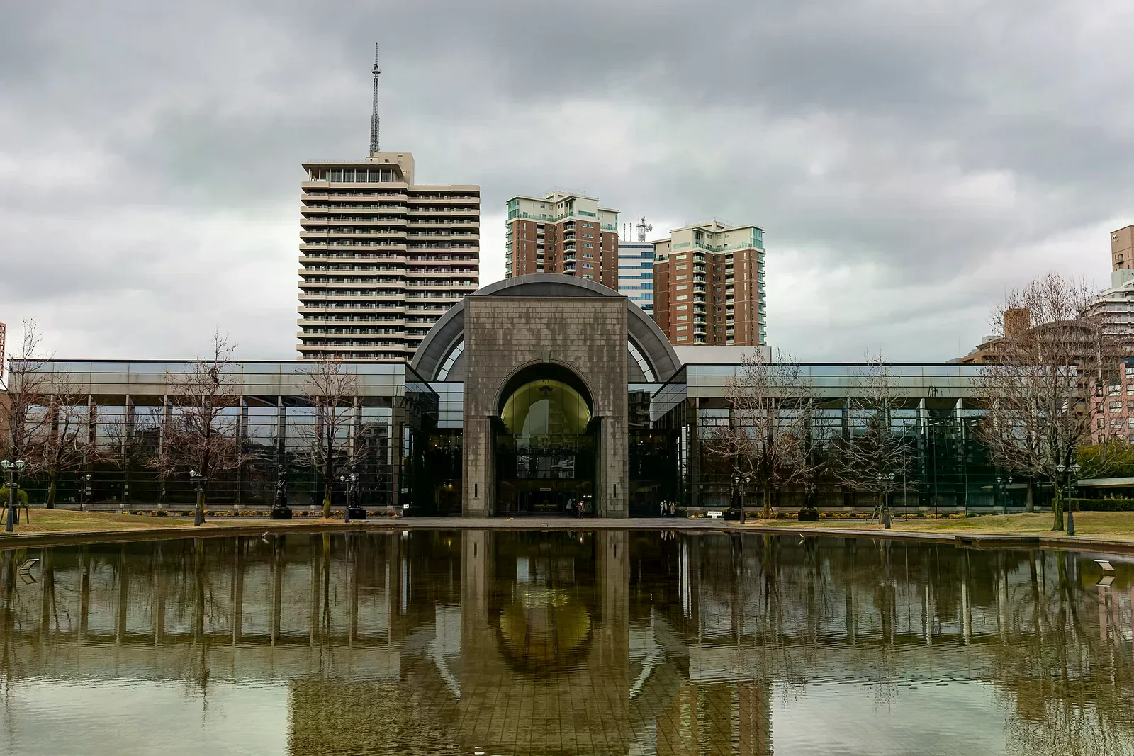 福岡市博物館入口與門前水池，陰天的廣場與後方高樓