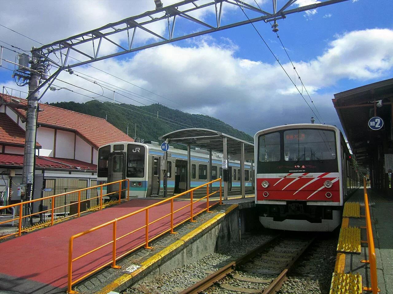 河口湖站月台停靠的富士急行6000系與JR東日本211系兩列車